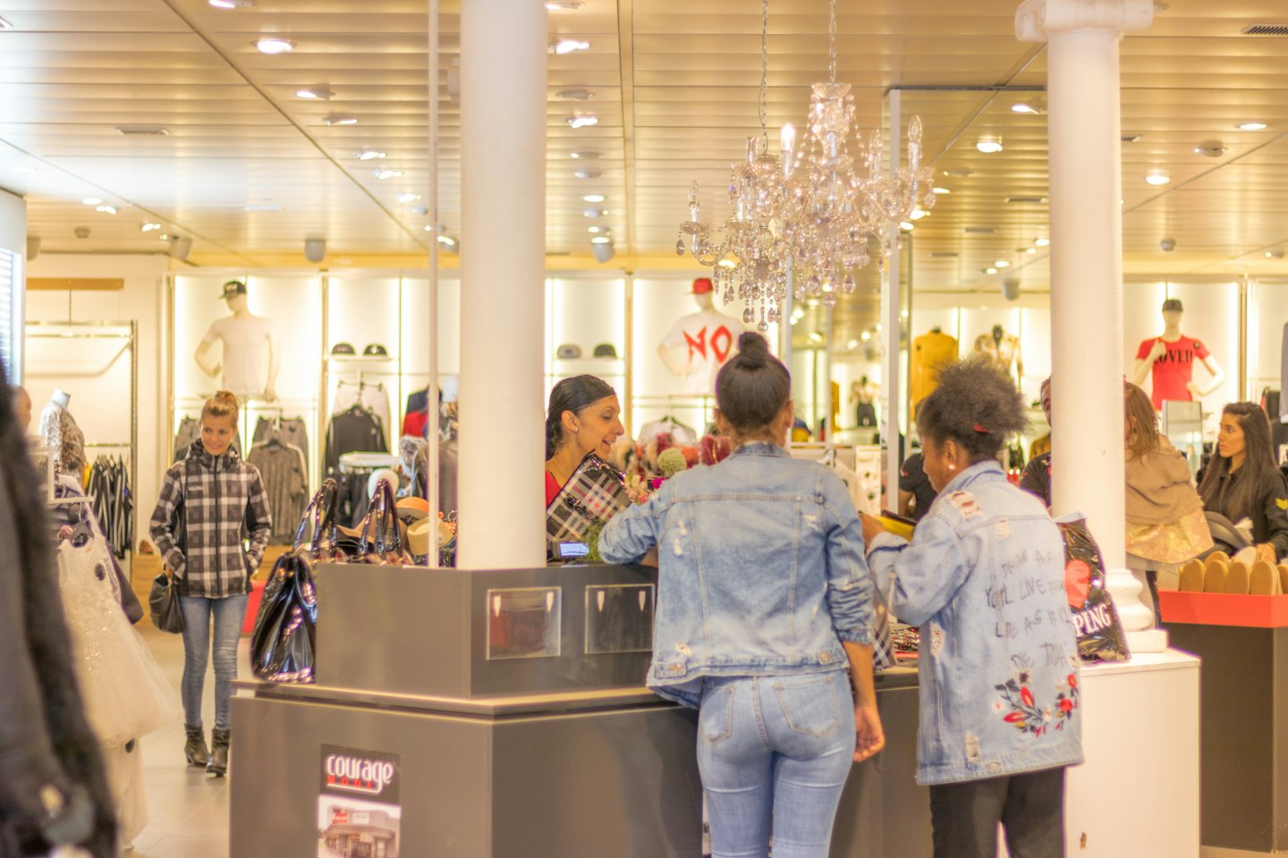 Sales associate helps customers at a clothing store checkout.