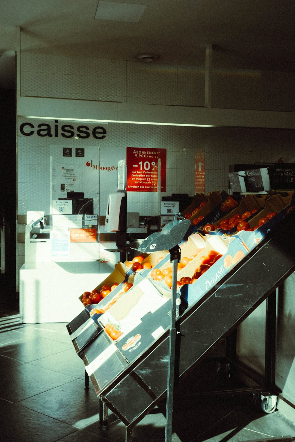 Fresh tomatoes and oranges sit on a tiered store display.